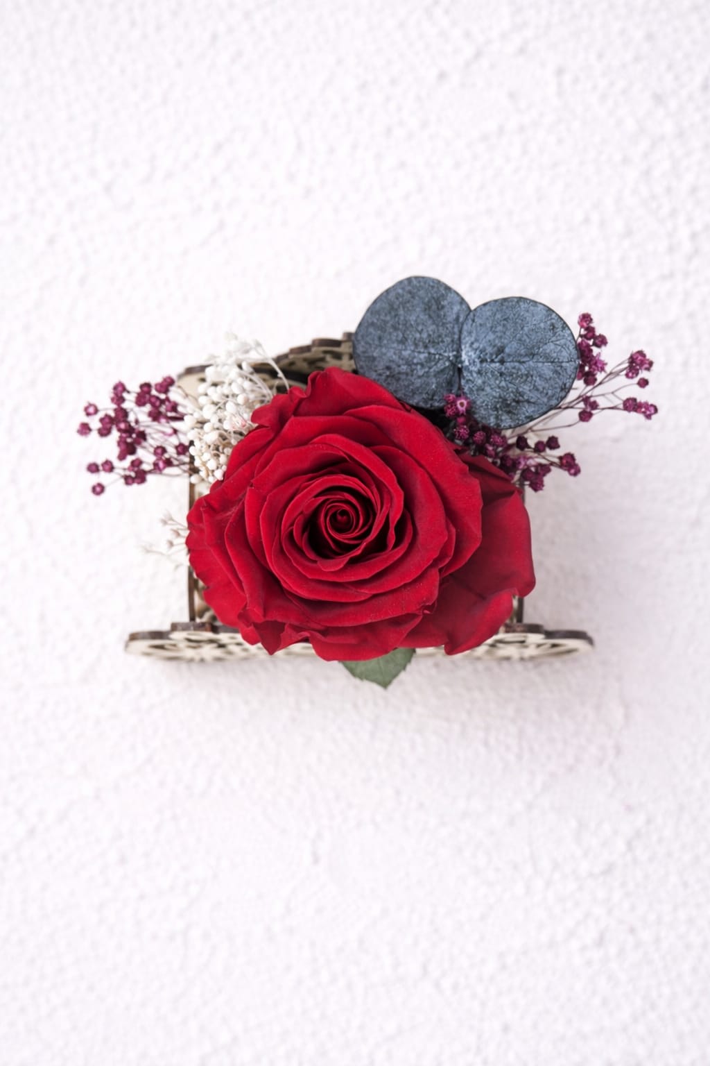 Vista superior de rosa eterna roja en carruaje de madera grabado con flores secas