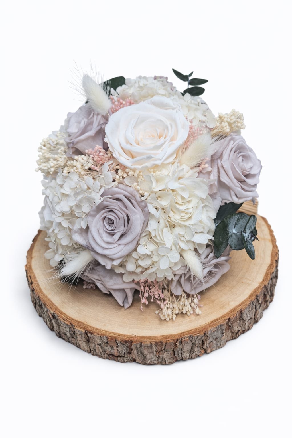 Ramo de novia con flores preservadas en tonos crema y nude sobre base de madera natural