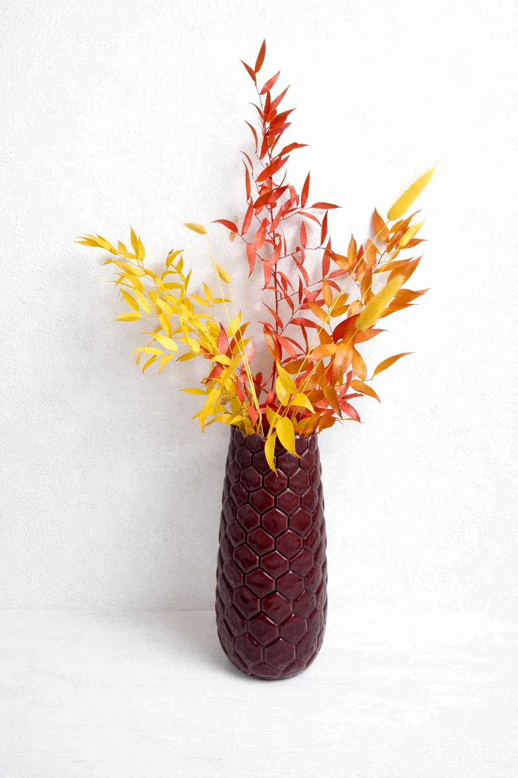 Ramo decorativo de hojas preservadas en tonos otoñales sobre fondo blanco