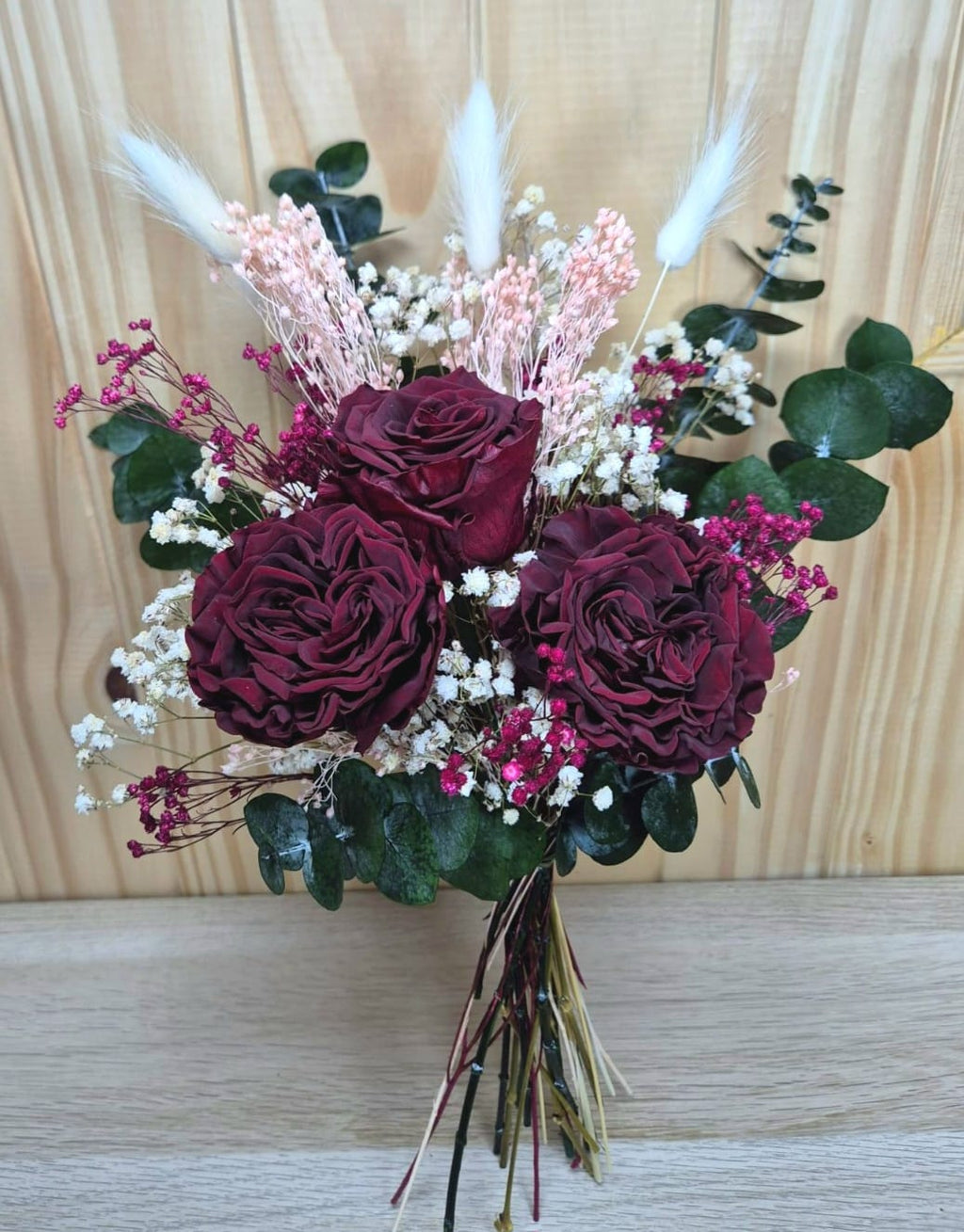 Ramo de flores secas con rosas burdeos y pampas sobre fondo blanco