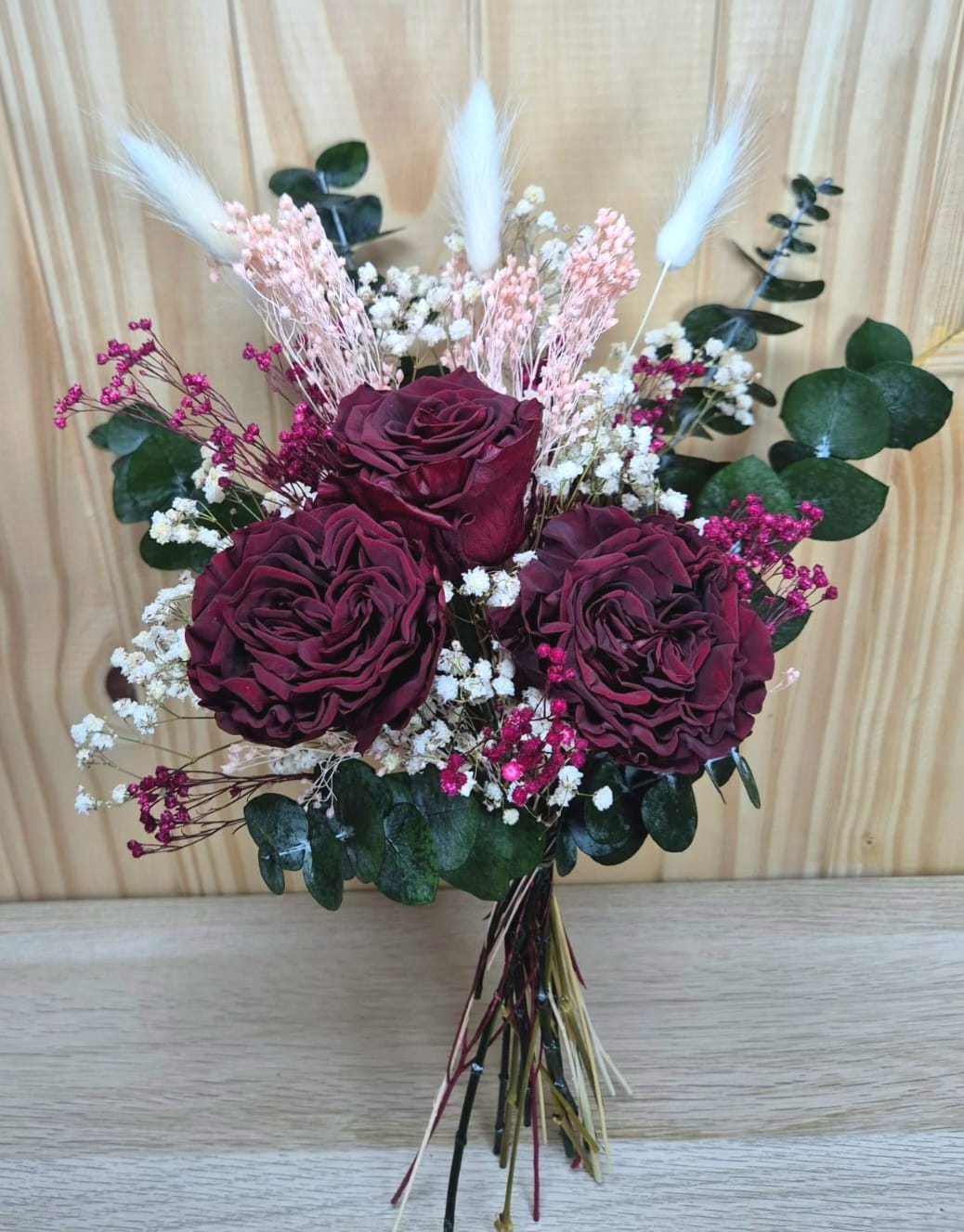 Ramo de flores secas con rosas burdeos y pampas sobre fondo blanco