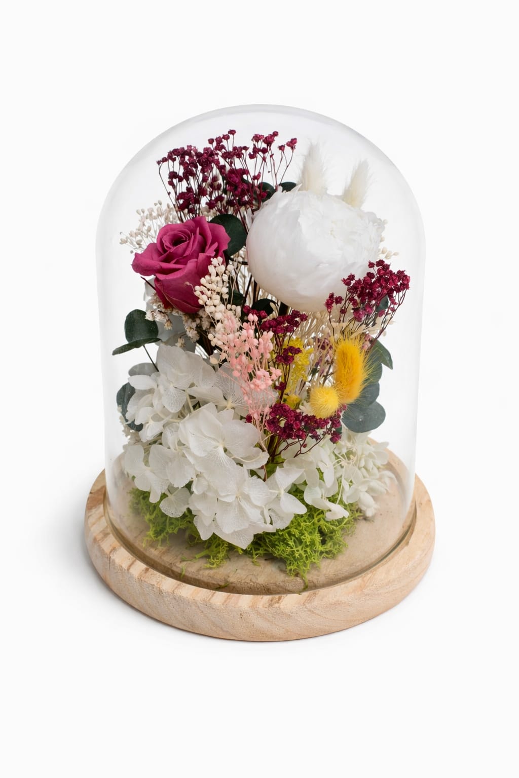 Cúpula de cristal con flores preservadas en tonos blancos, rosados y burdeos sobre base de madera natural